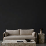 Beige Offset Sofa before a dark wall, styled with a Plinth Grand table, Plinth Tall table, and a Reverse Table Lamp.