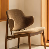 The Penguin Wooden Lounge Chair, fully upholstered in Logan Nutmeg fabric, styled in a minimalist interior corner.