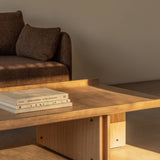 Natural oak Conrad Lounge Table with curved edges and exposed screws, styled next to a textured brown Offset Sofa.