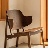 The Penguin Wooden Lounge Chair in red-stained oak, showcasing its curved, unupholstered form in a minimalist interior.