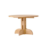 Puffin Dining Table in natural solid oak with a round top and architectural base, isolated on a white background.