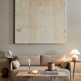 A living room with a beige Offset Sofa, a marble Androgyne Lounge Table, and a large abstract painting on the wall.