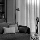 A black and white shot of the Offset Sofa in a living room setting, beside a marble Plinth and in front of a floor lamp.
