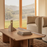 Natural oak Conrad Lounge Table on a Tile Rug, paired with Eave Seamline Lounge Chairs overlooking a scenic landscape.