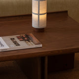 Conrad Lounge Table in dark stained oak veneer featuring an upward-curving border, styled with a portable lamp and magazine.